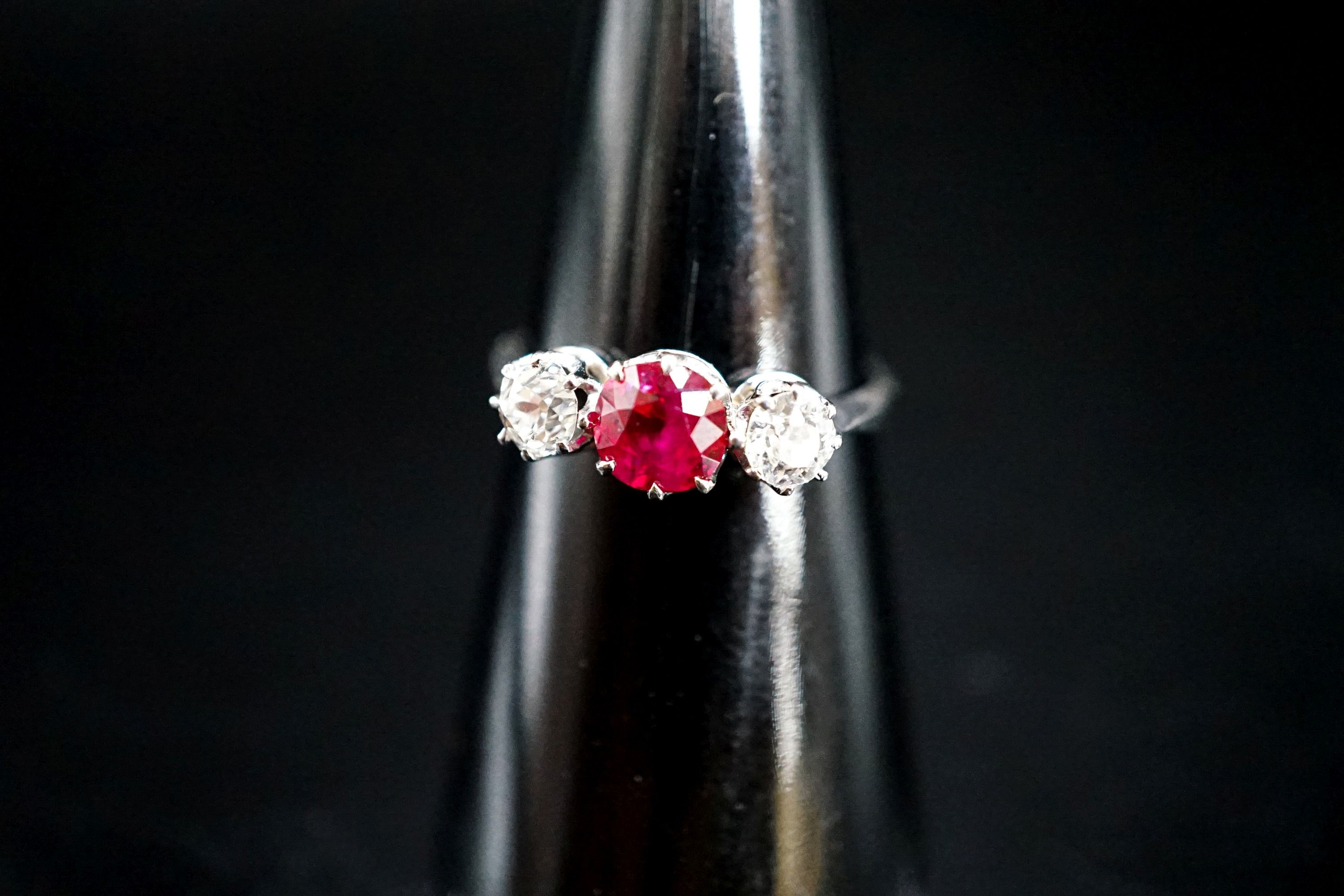 A white metal single stone ruby and two stone diamond ring, size L/M, gross weight 3 grams.